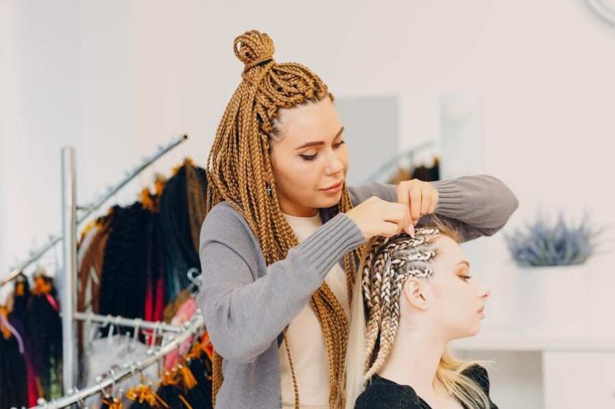 A girl making hair of another girl in crochet hair style