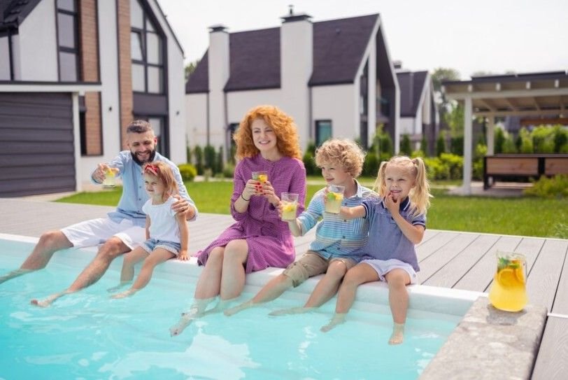 A couple with his children sitting beside wading pool