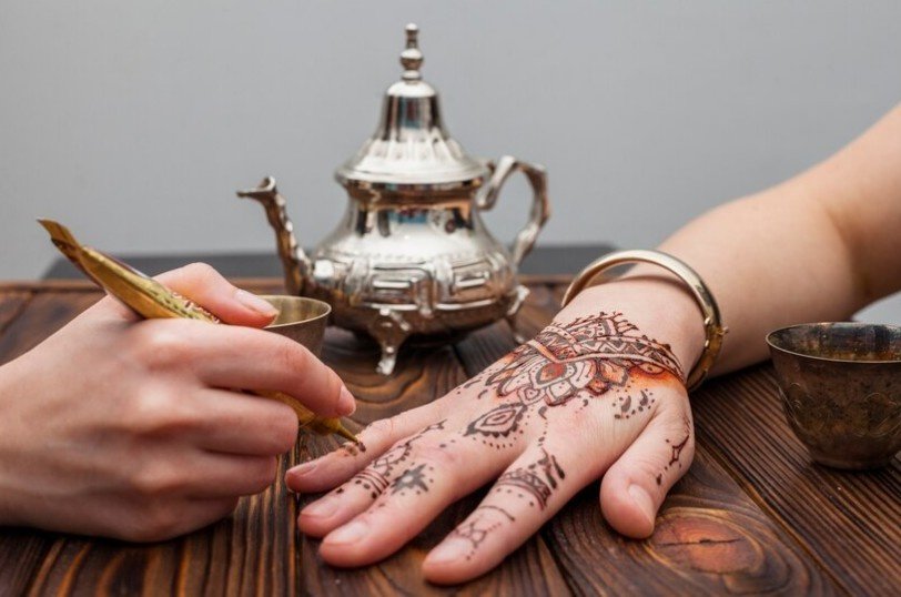 A mehndi expert applying mehndi designs on woman hands