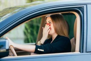 Girl driving with hand on nose to stop smell