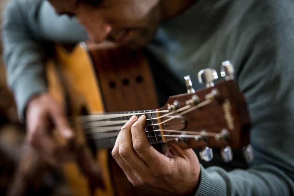 A young man playing a guitar in his hands