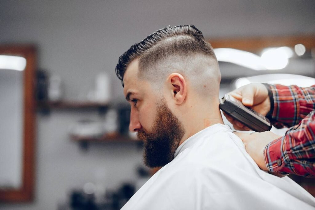 Barber cutting a guy's hair with hair cutting machine