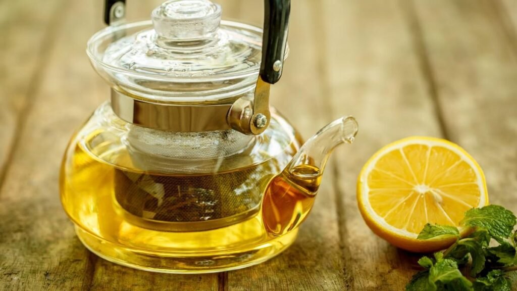 Transparent kettle within tea placed beside a lemon