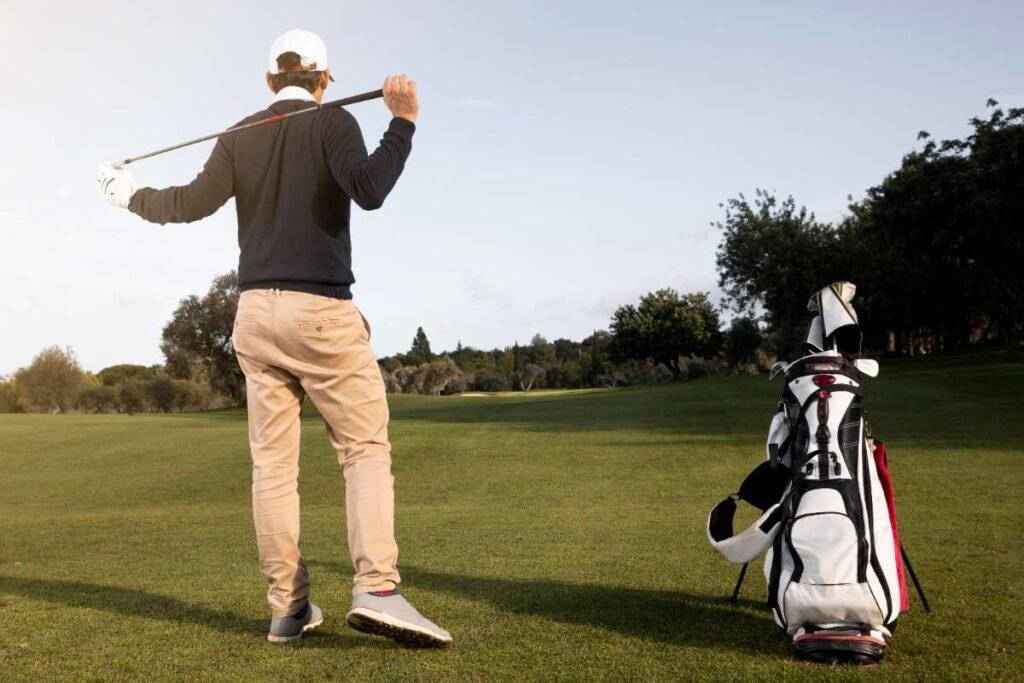 Golf player standing with golf stick in field.