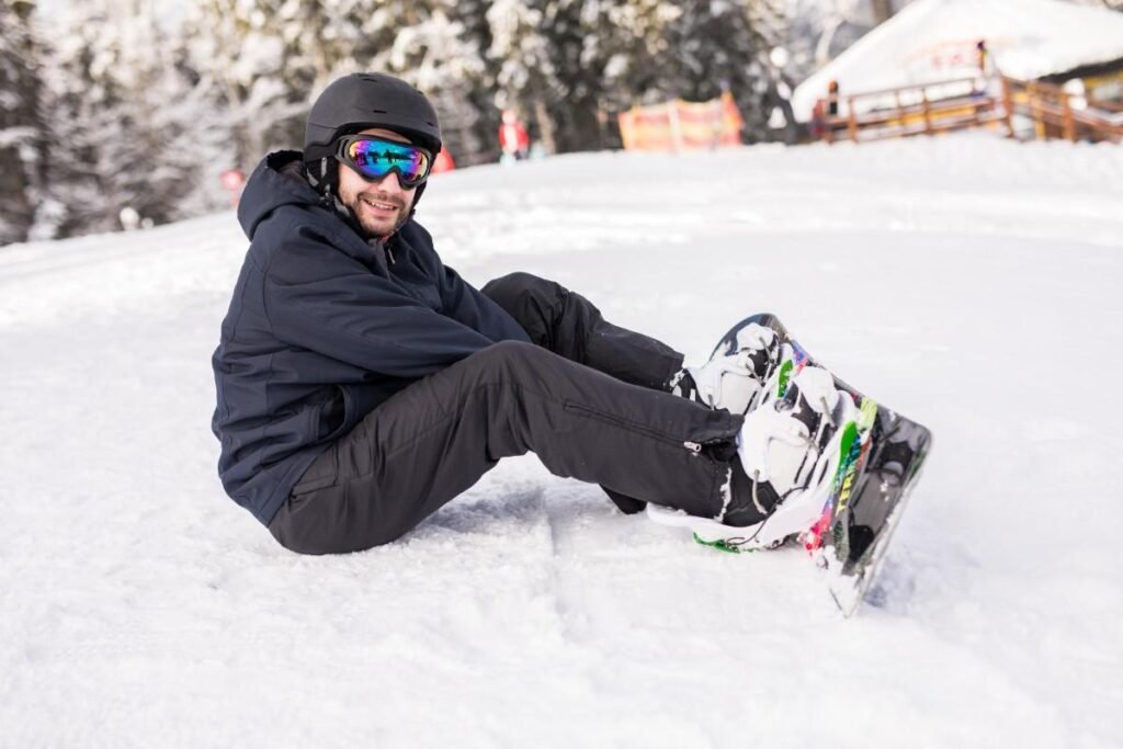 Snowboarder sitting on snow in black outfit