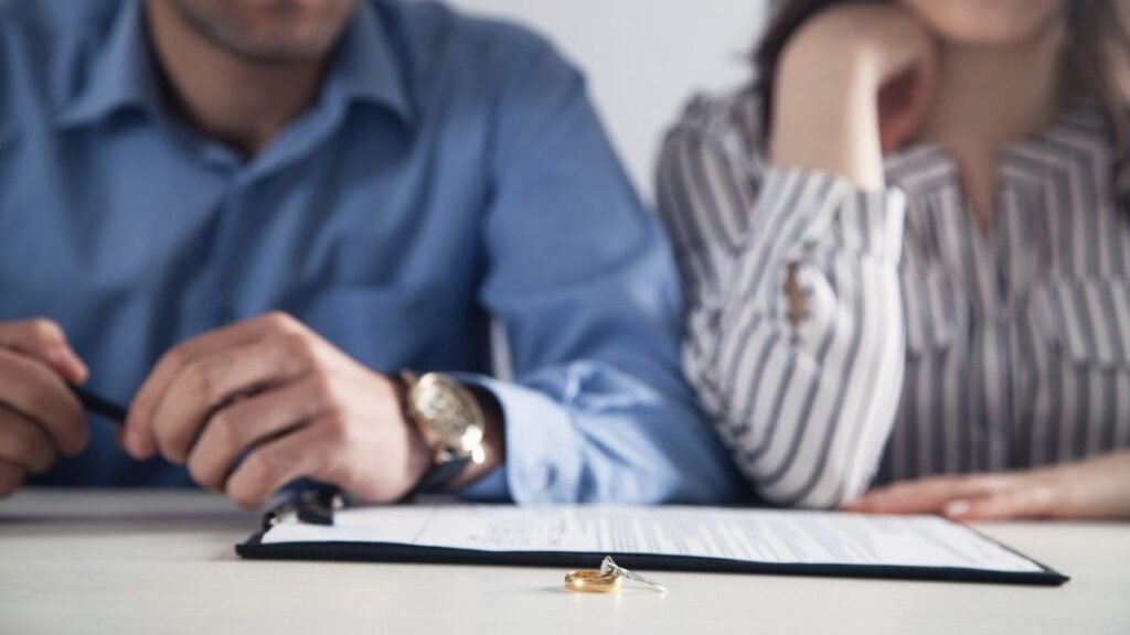 Couple with divorce contract and ring on desk