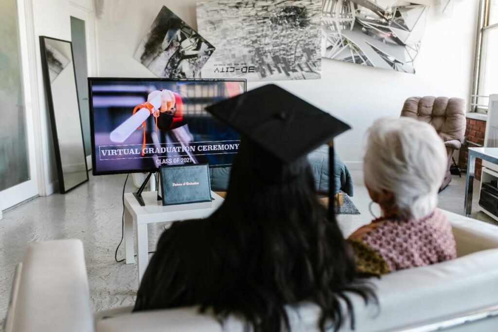 A girl Wearing Graduation Cap Attending Virtual Graduation Ceremony with an Elderly
